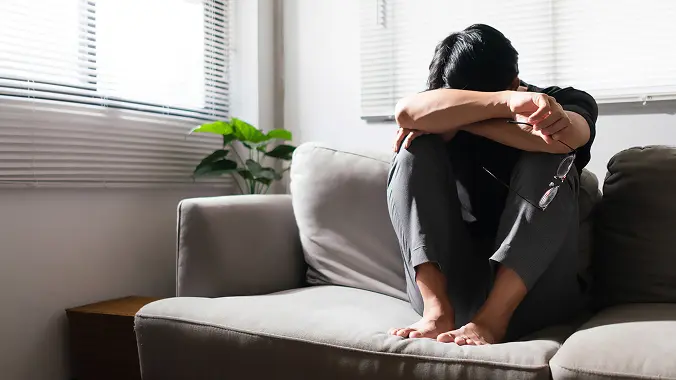 a man sitting on the couch as looking depressed and worried, Mental Health Impacts of Air Pollution