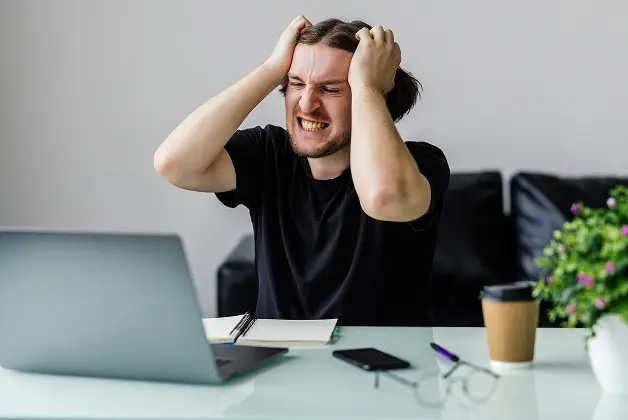 a man working in front of the laptop looking frustrated