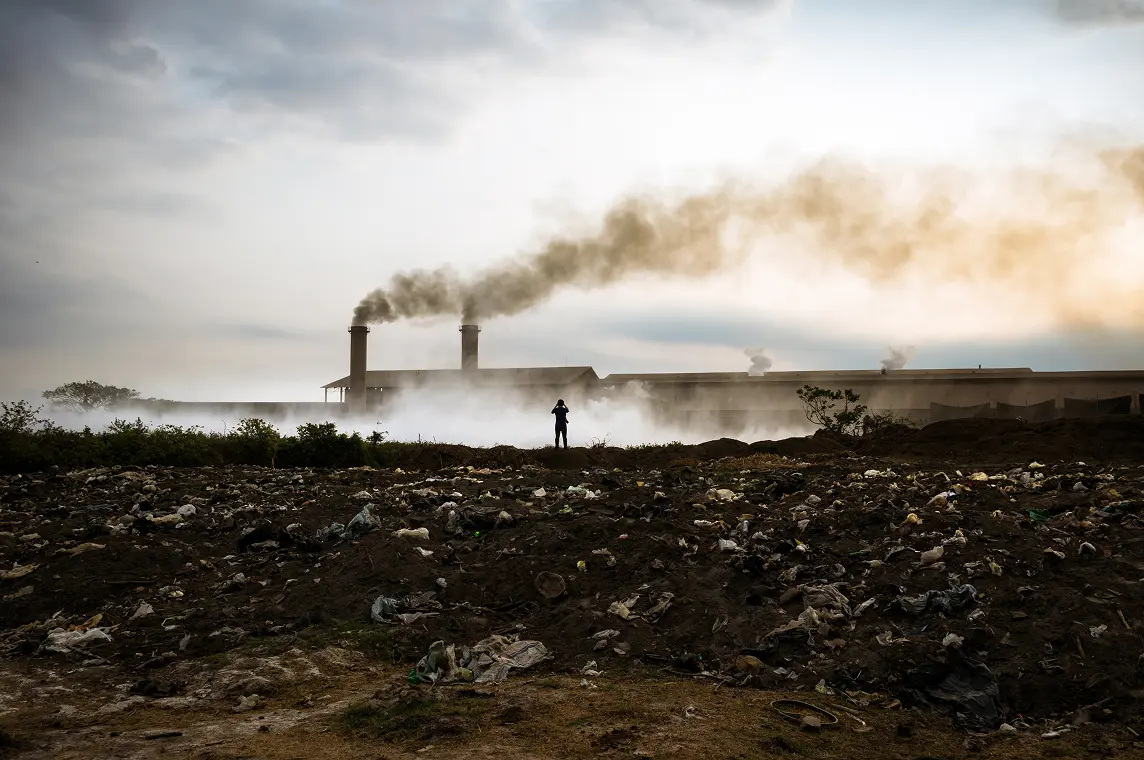 factory emitting dark smoke in the sky and ground covered with air pollution