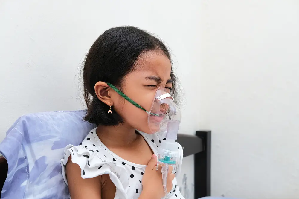 A kid inhaling with nebulizer attached to the face as facing problem in breathing