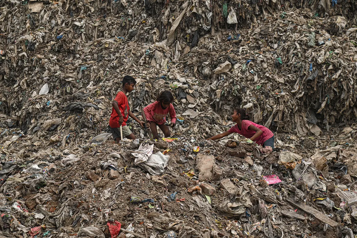 3 children picking up the garbage in a landfill