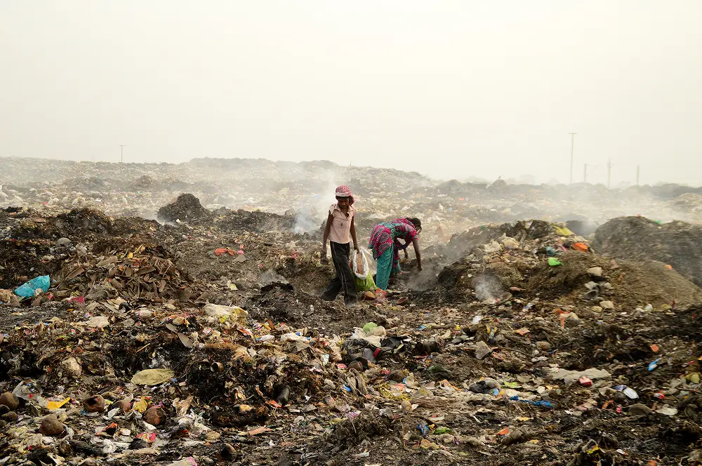 Plastic pollution in India: Ragpickers picking and searching recyclable material in landfill